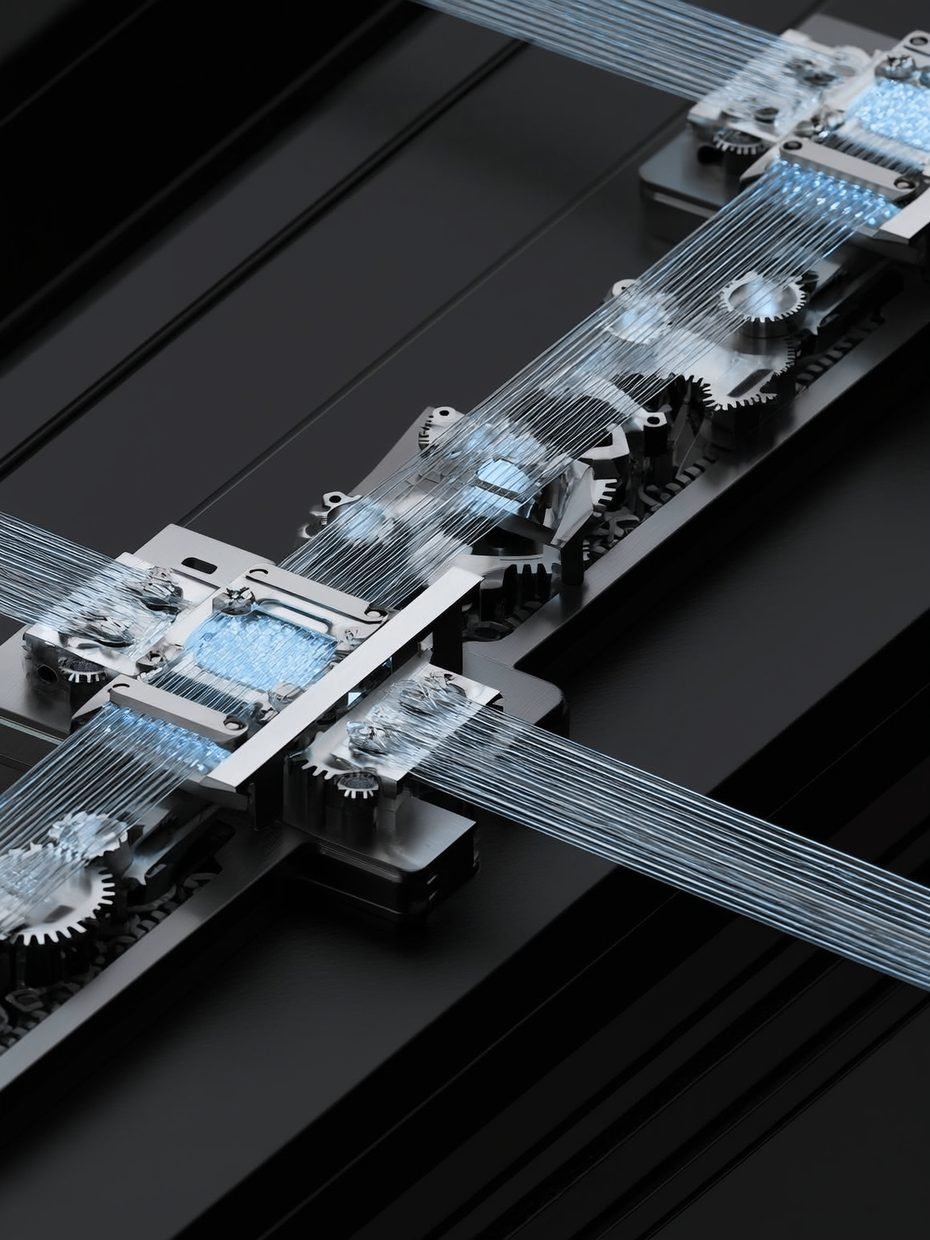 A brushed-silver mechanism of gears and glass fibres carrying ice-blue light between glowing nodes